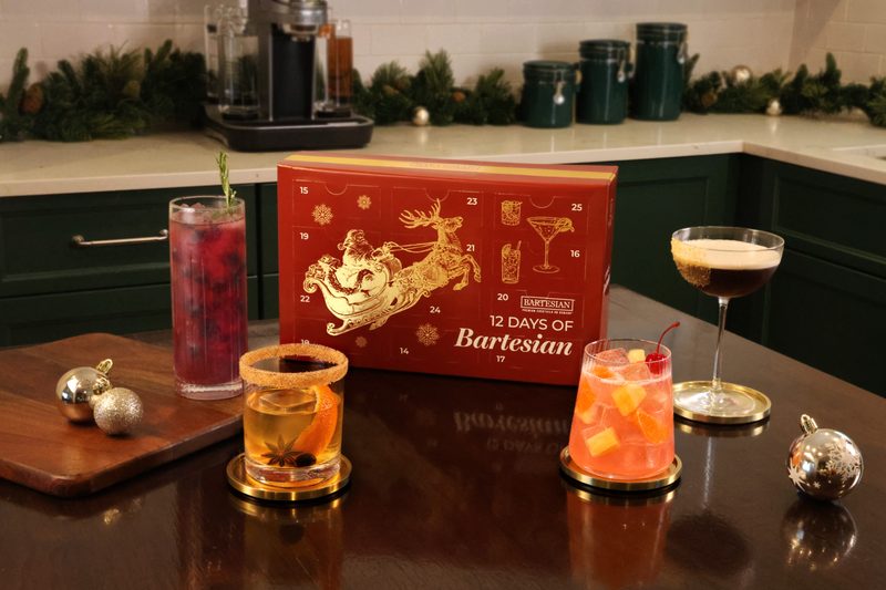 Four finished holiday cocktails on a counter in front of the Advent Calendar box