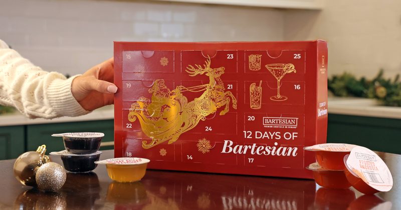 The 12 Days of Bartesian Advent Calendar box on a kitchen counter with cocktail capsules beside it