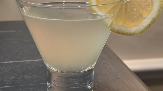 Bartesian Lemon Drop cocktail in a stemless martini glass with a lemon wheel, hazy pale yellow, on a home bar