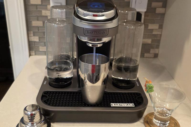 The Bartesian Premier pouring Sour Spell into a stainless steel shaker, with a stemless martini glass and a sour candy pick beside it