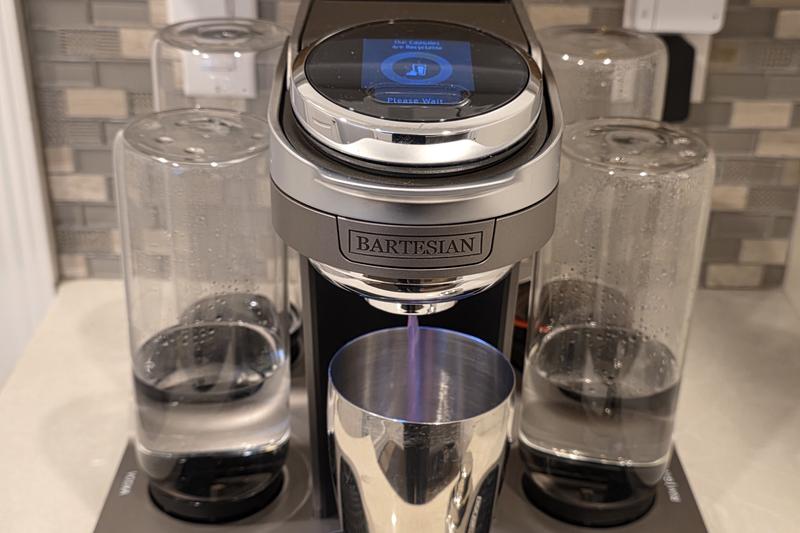 The Bartesian Premier pouring the purple Witch's Heart cocktail into a stainless steel shaker