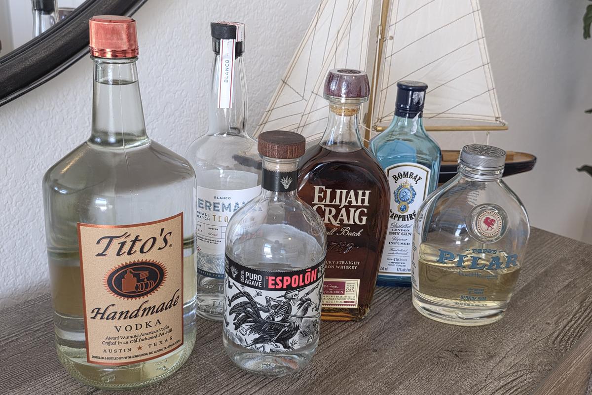 The six bottles I pour, lined up on a dresser: Tito's vodka, Teremana and Espolon tequila, Elijah Craig bourbon, Bombay Sapphire gin and Papa's Pilar blonde rum