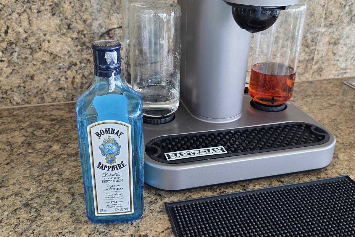 A blue bottle of Bombay Sapphire London Dry gin standing beside the Bartesian machine on a granite counter